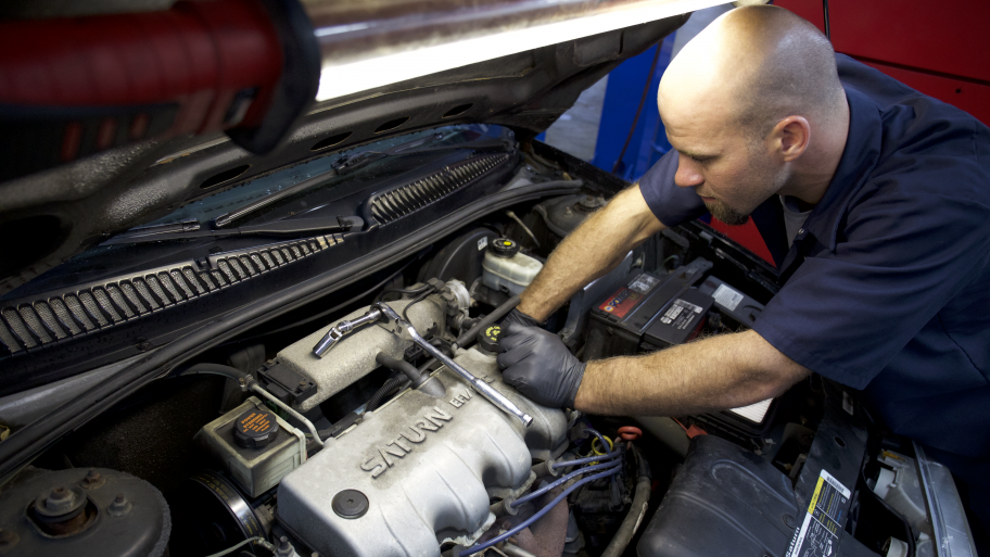 Mechanic working under the hood of a Saturn car